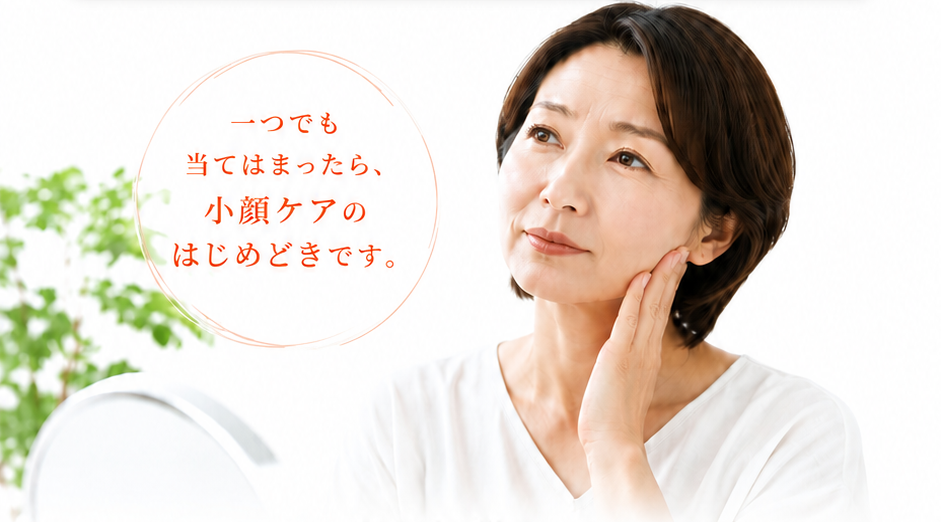 鏡を見ながら頬に手を当てる女性。一つでも当てはまったら、小顔ケアのはじめどきです。